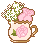 An image of a white cup with a gold rim with the image of a pink rose on it. It has a rose and little white flowers inside.